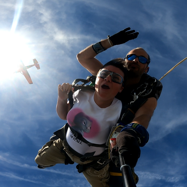 Saut en tandem face au soleil, la passagère souriante